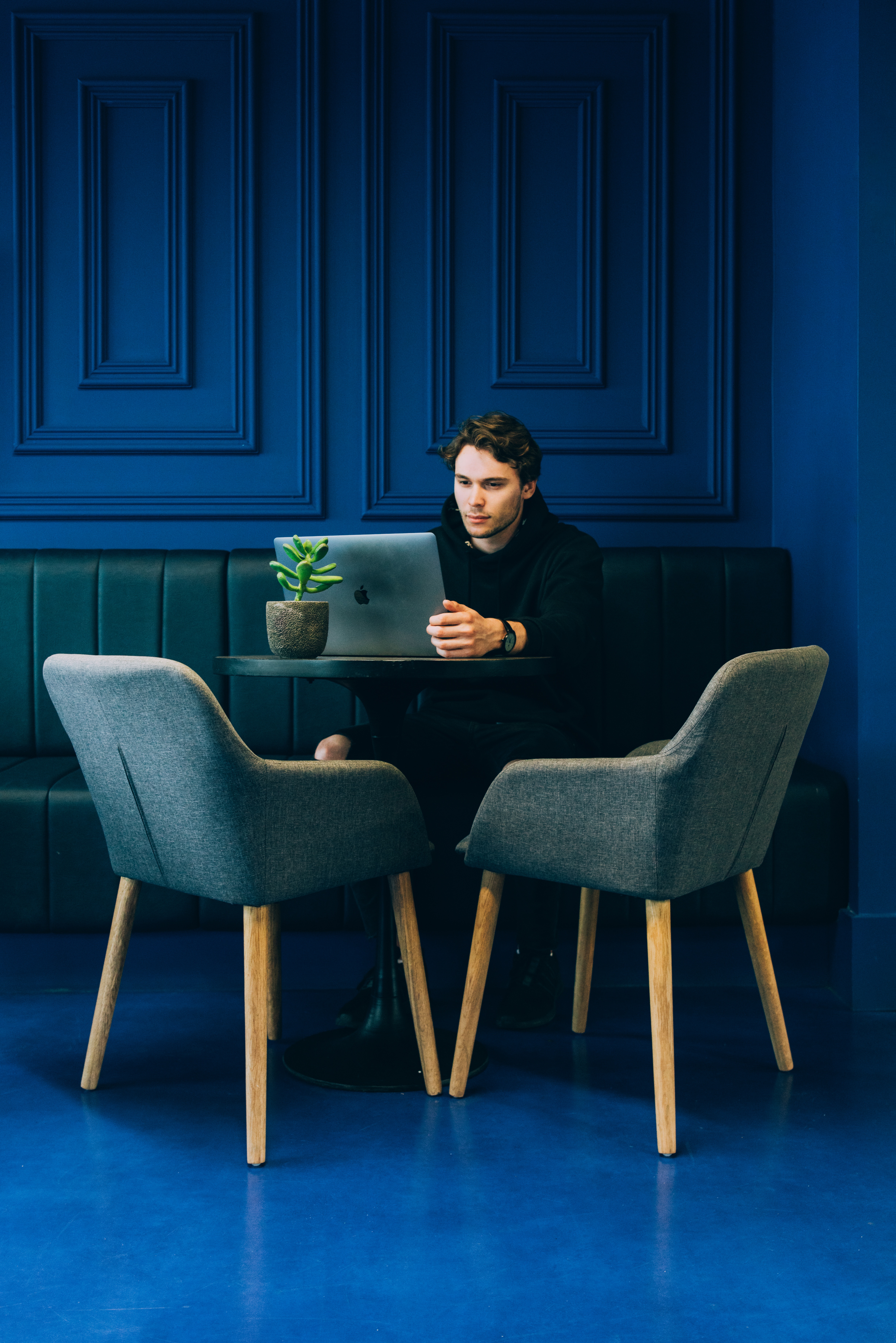 Homme assis à table sur banquette avec un ordinateur portable